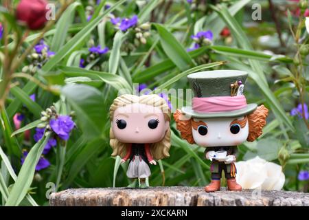 Funko Pop Actionfiguren von Mad Hatter und Alice im Wunderland aus dem beliebten Tim Burton Fantasy-Film. Blumen, fabelhafter Garten, Holzstumpf. Stockfoto