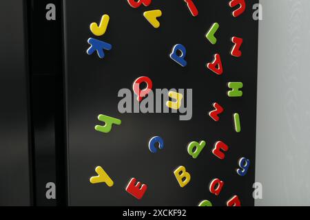 Viele helle magnetische Buchstaben auf dem Kühlschrank in Innenräumen. Alphabet lernen Stockfoto