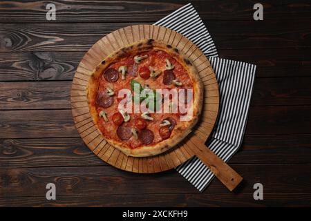 Köstliche Pizza mit Salami, Tomaten, Pilzen und Basilikum auf Holztisch, Blick von oben Stockfoto