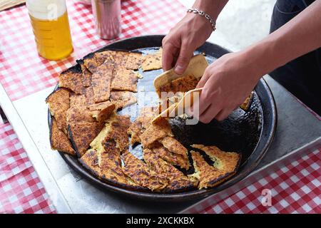 Socca, die gerade aus dem Ofen kommt, in Nizza, an der französischen Riviera. Socca ist eine Art dünner Socca, eine Spezialität der südöstlichen französischen Küche. Ein Pfannkuchen gemacht Stockfoto