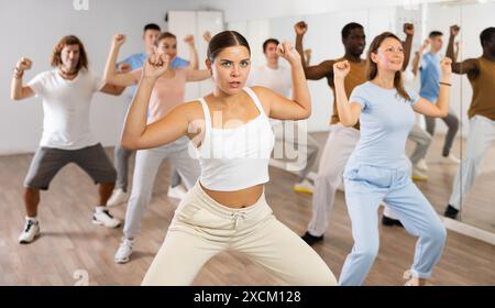 Fröhliche, energetische, multirassische Tänzer unterschiedlichen Alters, die Aerobic im Unterricht in der modernen Fitnessklasse tanzen Stockfoto