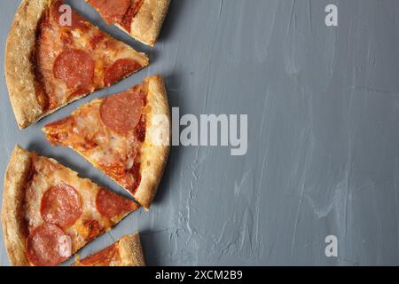 Rand von Peperoni-Scheiben Pizza mit Käse und Wurst auf grauem Hintergrund mit Platz für Text Copyspace oberer Winkel. Stockfoto