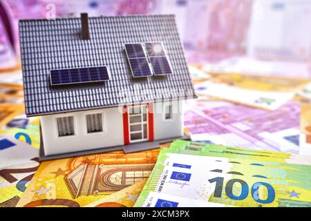 Deutschland - 17. Juni 2024: Energiewende - Solarsystem auf dem Dach eines Wohnhauses. Einfamilienhaus neben Banknoten und Euro-Banknoten. Konzept zur Förderung von Solarenergie und erneuerbaren Energien in Deutschland. PHOTOMONTAGE *** Energiewende - Solaranlage auf einem Dach eines Wohn-Gebäudes. Einfamilienhaus neben Geld-Scheinen und Euro Banknoten. Konzept zur Förderung der Solar-Energie und erneuerbaren Energien in Deutschland. Stockfoto