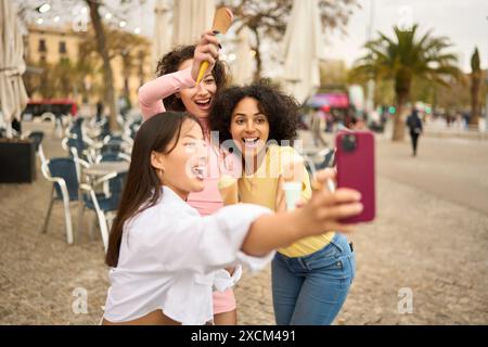 Junge Frauen genießen Eis und machen Selfie im Freien Stockfoto
