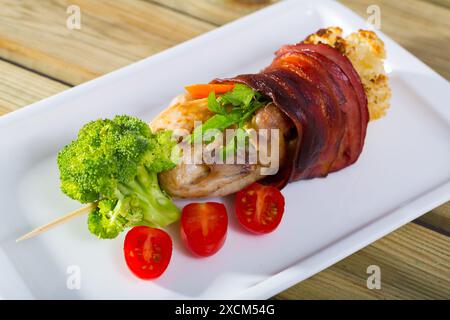 Gegrillte Wachteln im Jamon auf Spieß mit Gemüse Stockfoto