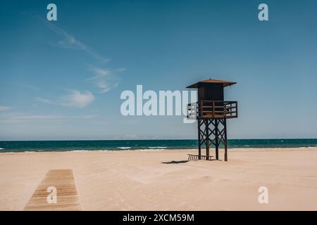 Ein einsamer Rettungsschwimmer-Turm, der an einem leeren Sandstrand mit Meer und Himmel im Hintergrund steht. Strand Sant Antoni, Cullera, Spanien Stockfoto