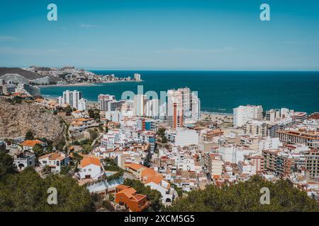 Ein Panoramablick auf eine Küstenstadt mit verschiedenen Gebäuden und das Meer im Hintergrund. Strand Sant Antoni, Cullera, Spanien Stockfoto