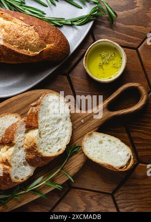 Französisches Baguette mit Olivenöl und frischem Rosmarin auf einem Küchentisch Stockfoto
