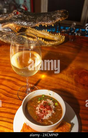 New Orleans Gumbo mit Wein und einem Alligatorkopf im Hintergrund Stockfoto