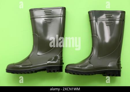 Grüne Gummistiefel auf farbigem Hintergrund Stockfoto