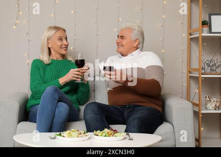 Glückliches reifes Paar mit Gläsern Wein zu Hause Stockfoto