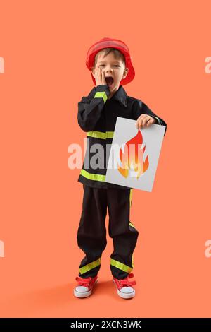 Schockierte kleine Feuerwehr mit Papierflamme auf orangem Hintergrund Stockfoto