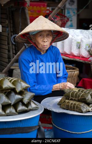 Ältere Hmong-Frau, die Lebensmittel auf dem Markt Bac Ha in der Provinz Lao Cai, Vietnam verkauft Stockfoto