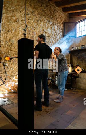 Handwerker von Frauen und Männern, die in einer handgefertigten Glasbläserwerkstatt arbeiten Stockfoto