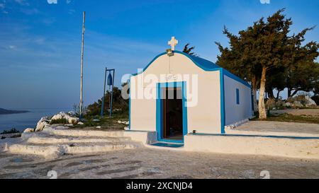 Profitis Ilias Chapel, kleine weiße Kapelle vor einer ländlichen Landschaft mit blauem Himmel und umgeben von Bäumen, Anthony Quinn Bay, Vagies Bay, Rhodos Stockfoto