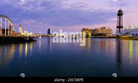 BARCELONA, SPANIEN. August 2022. Eine Skyline der Stadt mit einem großen Gebäude im Hintergrund. Das Wasser ist ruhig und der Himmel ist eine Mischung aus Blau und Lila. Stockfoto