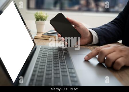 Mann, der einen Laptop benutzt, der einen Mock-up-Computer ansieht, der einen leeren Bildschirm, einen weißen Computerbildschirm, zu Hause ansieht Stockfoto