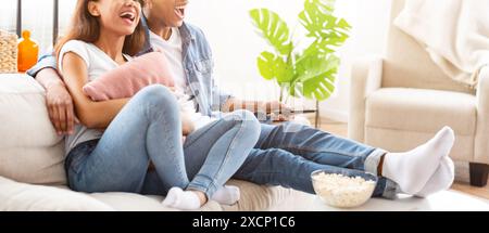 Paare, die sich auf der Couch entspannen und im Wohnzimmer Fernsehen schauen, Cropped Stockfoto
