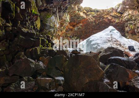 Der Lavatunnel (Raufarholshellir) in Island, Innenansicht des Eingangs zur Lavaröhre mit eingestürzter Decke, Steinen und Schnee. Stockfoto