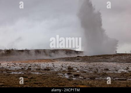 Strokkur-Geysir bricht aus, Springbrunnen-Typ-Geysir im geothermischen Gebiet Islands, Menschen beobachten im Hintergrund. Stockfoto