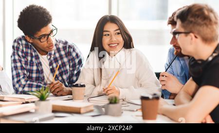 Fröhliche Studenten der multiracial Hochschule, die mit Büchern in der Bibliothek studieren Stockfoto