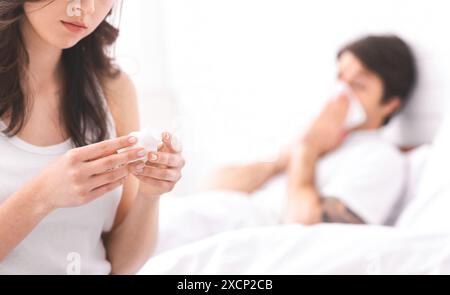 Eine Frau hält Serviette, während der kranke Partner im Bett liegt Stockfoto