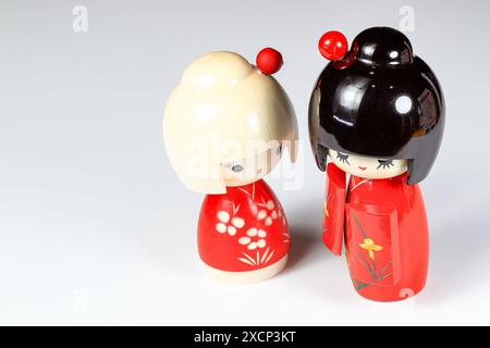 Japanische Holzpuppen „kokeshi“ im roten Kimono-Anzug, Spielzeug für eine Dekoration, Souvenir aus Japan isoliert auf weißem Hintergrund. Stockfoto