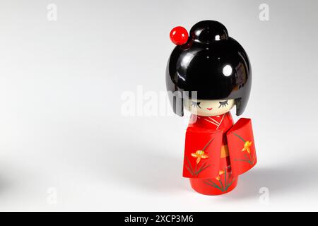Japanische Holzpuppen „kokeshi“ im roten Kimono-Anzug, Spielzeug für eine Dekoration, Souvenir aus Japan isoliert auf weißem Hintergrund. Stockfoto