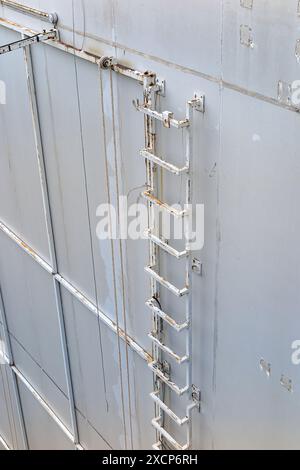 Vertikale alte Metalltreppe, Industrie ohne Sicherheitsschienen an der Wand des alten Industriebaus. Stockfoto