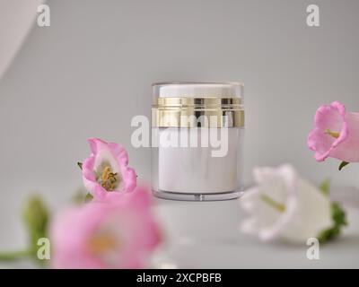 Hautpflegeprodukte auf neutralem Hintergrund. Mockup-Flaschen und Blumen mit Kopierraum. Gesichtscreme und Körperlotion Stockfoto