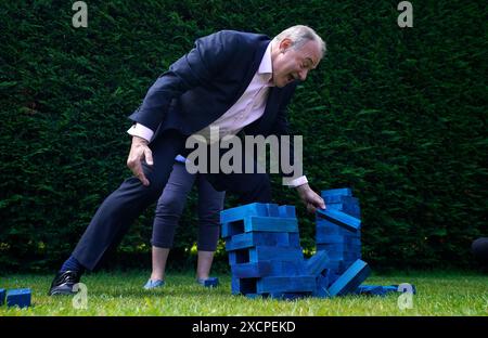 Der Vorsitzende der Liberaldemokraten Sir Ed Davey und der Kandidat der Liberaldemokraten für Eastleigh Liz Jarvis spielen Jenga mit blauen Jenga-Blöcken, die die Sitze der Konservativen Partei repräsentieren, während sie auf der Crowd Hill Farm in Hampshire unterwegs sind. Bilddatum: Dienstag, 18. Juni 2024. Stockfoto