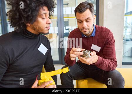 Zwei Ingenieure diskutieren Roboterkomponenten und untersuchen Teile, um Automatisierungsprozesse und Industrierobotik in einer modernen Umgebung zu verbessern. Stockfoto