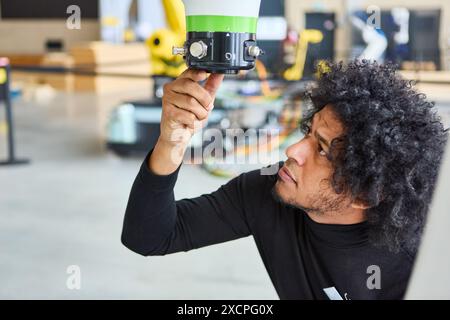Ein Ingenieur, der in einer High-Tech-Werkstatt einen Robotergreifer genau untersucht und dabei den Schwerpunkt auf fortschrittliche Robotik- und Automatisierungstechnologie legt. Stockfoto