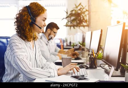 Frau mit Headset, die am Computer im Büro arbeitet Stockfoto