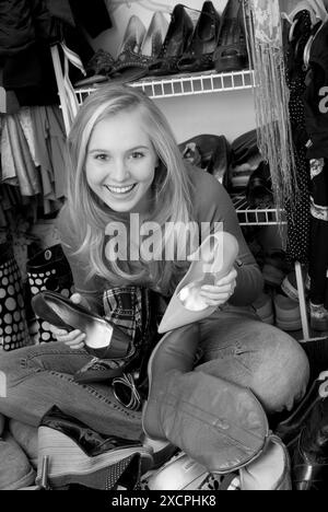 Ein lächelndes weißes Teenager-Mädchen, das Schuhe aus ihrem Schrank aussucht, USA. Stockfoto