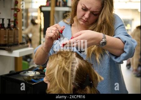 Frau, die Haarfärbung von einem professionellen Friseur in einem Schönheitssalon erhält. Konzentriert sich auf den Friseur, der Farbe auf die Haare des Kunden aufträgt. Stockfoto