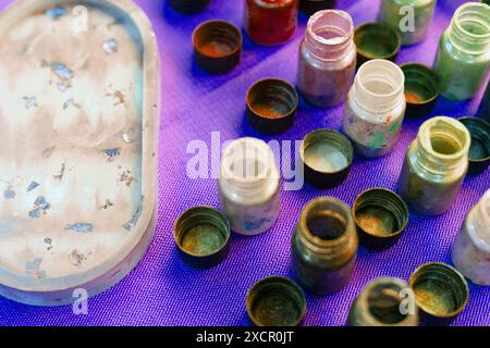 Farbflaschen für Kunstharzkunst. Mischen von Epoxid in Kunststoffbechern zur Gießstabilisierung und Hybridbehandlung. Kunstmalerei Stockfoto