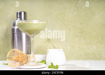 Cremiger Matcha-Martini-Cocktail Matchatini, trendiger kalter Sommercocktail. Matcha alkoholfreier Mocktail oder Alkohol Cocktail, in Martini Gläsern mit GREE Stockfoto