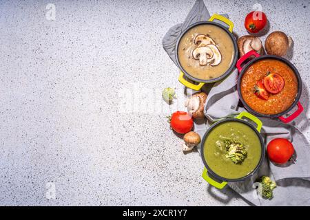 Herbstgemüsecremesuppen Set. Drei Portionstöpfe mit verschiedenen veganen heißen Gemüsesuppen – Tomaten, Pilze, Brokkoli auf weißem Tisch copy sp Stockfoto