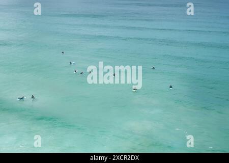 Ein Blick aus der Vogelperspektive auf Surfer, die im Meer auf eine Welle an der Küste von Newquay in Cornwall in Großbritannien warten. Stockfoto