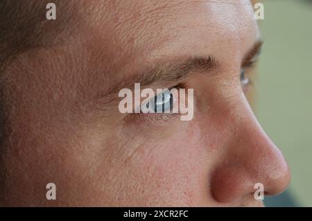 Das Gesicht und die Augen eines Mannes. Feine Linien im Gesicht eines jungen 28-jährigen Jungen. Nahaufnahme des Gesichts. Der Mann schaut in die Ferne. Stockfoto