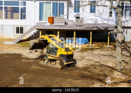 Auf dem Erdbewegungsgelände ebnet der Traktor den Boden während der Arbeiten an einem Hinterhofbauprojekt Stockfoto