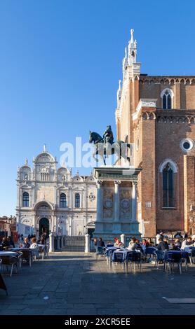 Scuola Grande di San Marco, Campo di San Giovani e Paolo, Venedig, Italien mit Touristen, die einen Drink unter der Statue von Bartolomeo Colleoni in Even genießen Stockfoto