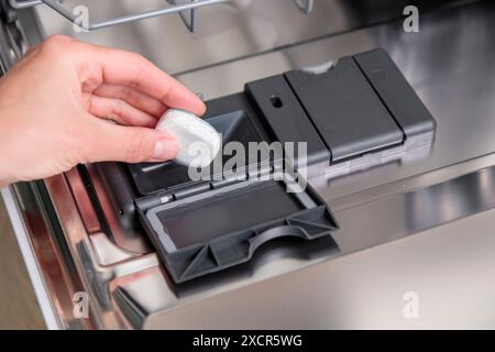 Geschirrspültabletten, Frau gibt die Kapsel in die Spülmaschine, bevor Geschirr und Besteck gewaschen werden. Bildausschnitt Stockfoto