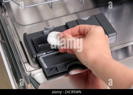 Geschirrspültabletten, Frau gibt die Kapsel in die Spülmaschine, bevor Geschirr und Besteck gewaschen werden. Bildausschnitt Stockfoto