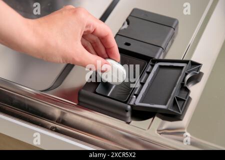 Geschirrspültabletten, Frau gibt die Kapsel in die Spülmaschine, bevor Geschirr und Besteck gewaschen werden. Bildausschnitt Stockfoto