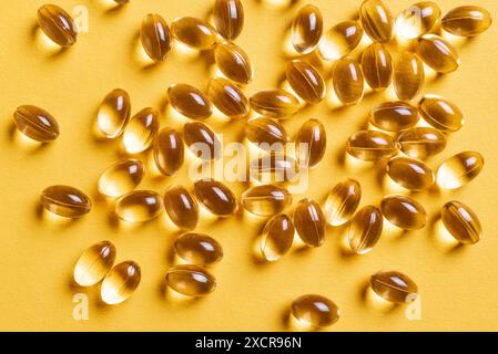 Fischöl Omega 3 Kapseln mit EPA und DHA, Vitamin D3, Vitamin E, Vitamin A Nahaufnahme auf gelbem Hintergrund. Gelbe Softgele mit LeberLeberLeberöl. Stockfoto