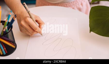 Lady zeichnet mit einem schwarzen Stift auf einem weißen Blatt Stockfoto