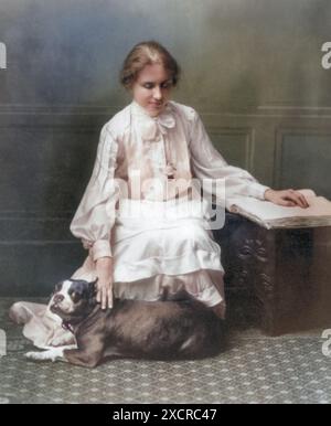 Hellen Keller mit ihrem Hund, liest ein Buch in Braille, 1904. Helen Keller (1880–1968) war eine US-amerikanische Autorin, politische Aktivistin und Dozentin. Sie war es Stockfoto