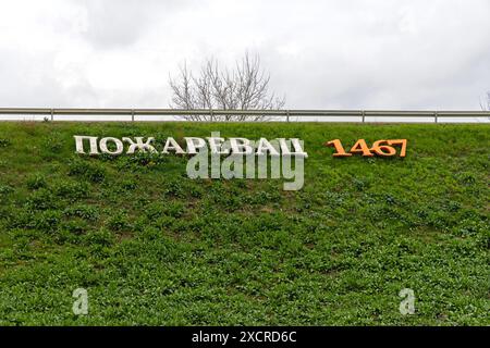 Pozarevac, Serbien - 14. März 2024: 3D-Zeichen kyrillische Schriftzeichen Pozarevac seit 1467 am Eingang zum städtischen Grassteg, Frühlingstag. Stockfoto